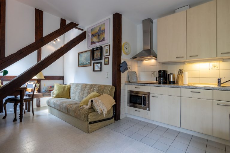 173A6564-HDR – Hubertus Boltenhagen Gemütliche Wohnküche mit Sofa, Holzbalken und dekorierten Wänden.