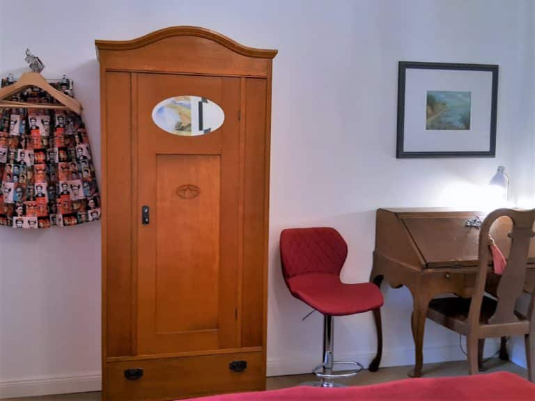 20220625_161121 (2) – Hubertus Boltenhagen Alter Holzschrank, roter Stuhl und Klavier im gemütlichen Raum.