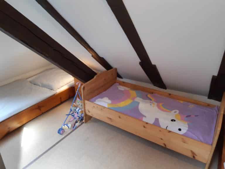 20220625_163216 – Hubertus Boltenhagen Holzbett mit Einhornbettwäsche unter Dachschrägen.