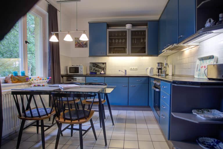Haus_Hubertus_-62-11 – Hubertus Boltenhagen Küche mit blauen Schränken, Esstisch und Hängelampen.
