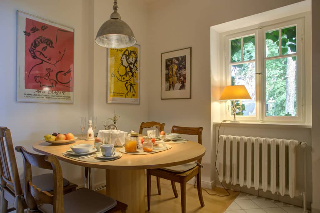 Gemütlicher Essbereich mit rundem Tisch, gedeckt für Frühstück, Wandkunst und warmem Licht.