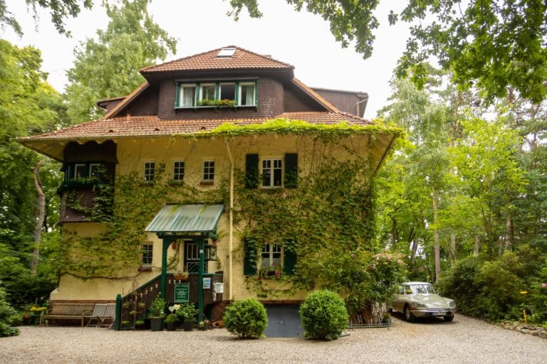 Haus_Hubertus_-7951 – Hubertus Boltenhagen Großes, mit Efeu bewachsenes Ziegelhaus mit grünen Fensterläden.
