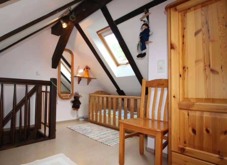 IMG_4756 (2) – Hubertus Boltenhagen Dachzimmer mit Holzmöbeln, schrägem Fenster, Babybett und Spielzeug.