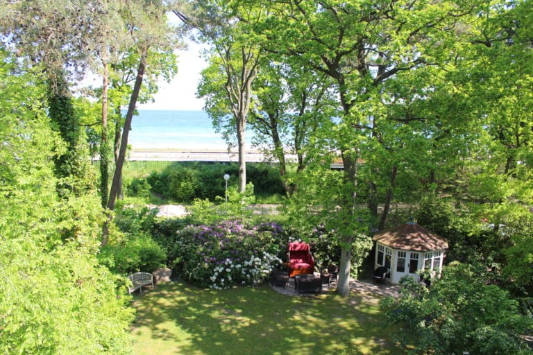 IMG_5287 – Hubertus Boltenhagen Grüner Garten mit Pavillon und Meerblick durch hohe Bäume.