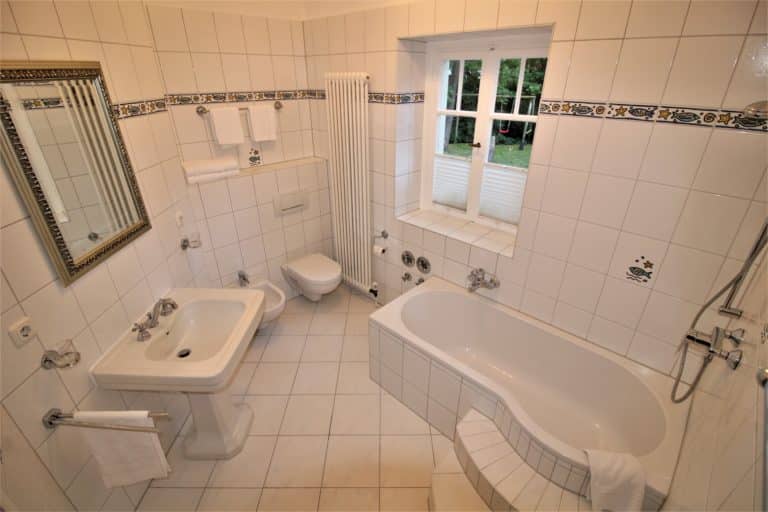 IMG_5536 (2) – Hubertus Boltenhagen Helles Badezimmer mit Badewanne, WC, Waschbecken und kleinem Fenster.