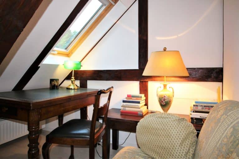 IMG_6158 (2) – Hubertus Boltenhagen Gemütliches Arbeitszimmer mit Dachfenster, Schreibtisch, Stuhl, Lampe und Bücherstapel.