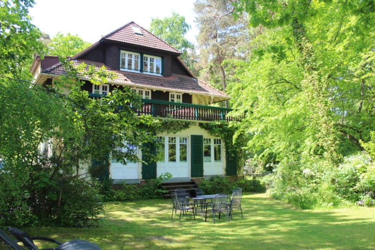 IMG_5337 – Hubertus Boltenhagen Zweistöckiges Haus im Grünen mit Terrasse und Gartenmöbeln.