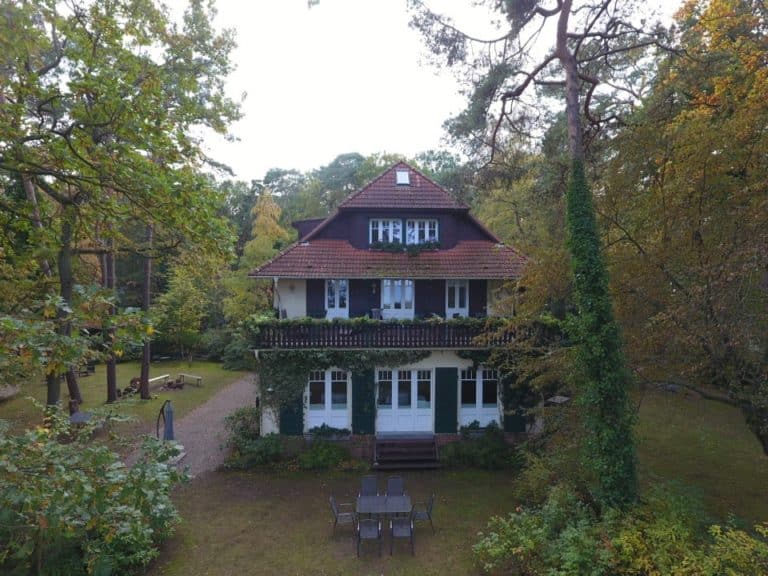 DJI_0029 (2) – Hubertus Boltenhagen Two-story house in the woods with a red roof and green shutters.