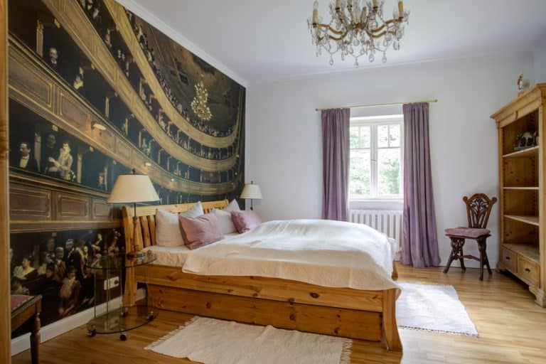 Haus_Hubertus_-7-17 – Hubertus Boltenhagen Cozy bedroom with wooden bed, chandelier and purple curtains.