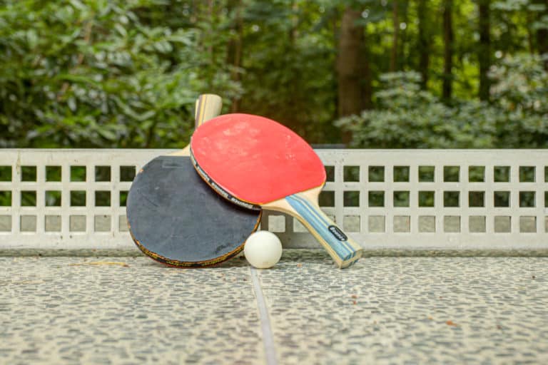 Haus_Hubertus_-7-48 – Hubertus Boltenhagen Two table tennis paddles and a ball on an outdoor patio table.