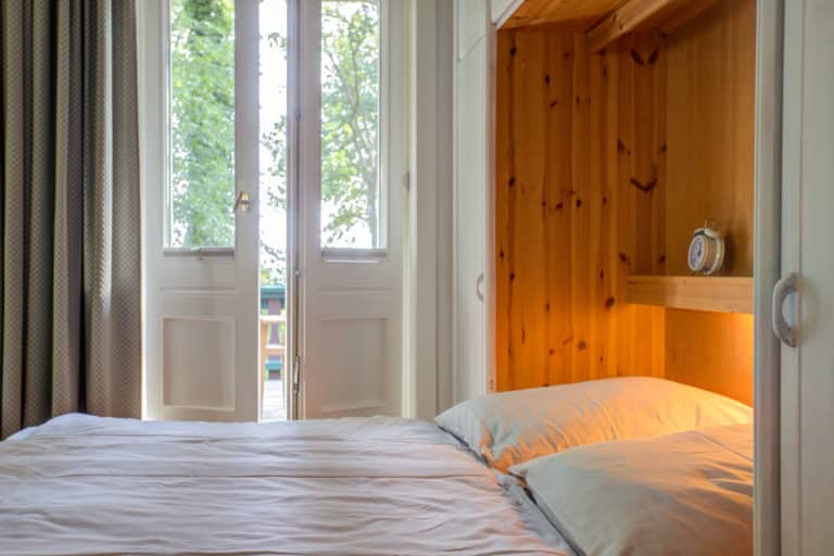 Haus_Hubertus_-7-6 – Hubertus Boltenhagen Cozy bedroom with wooden decor and view of the sunny garden terrace.