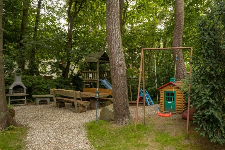 Haus_Hubertus_-7850 – Hubertus Boltenhagen Forest playground with wooden bench, swing and small climbing house.
