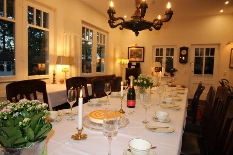 IMG_5597 – Hubertus Boltenhagen Festively set table with candles, sparkling wine and fine china in an elegant dining room.