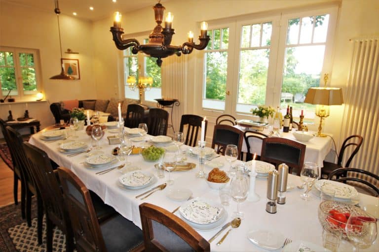 IMG_5625 (2) – Hubertus Boltenhagen Festively set dining table with white tablecloth and a candelabra above.