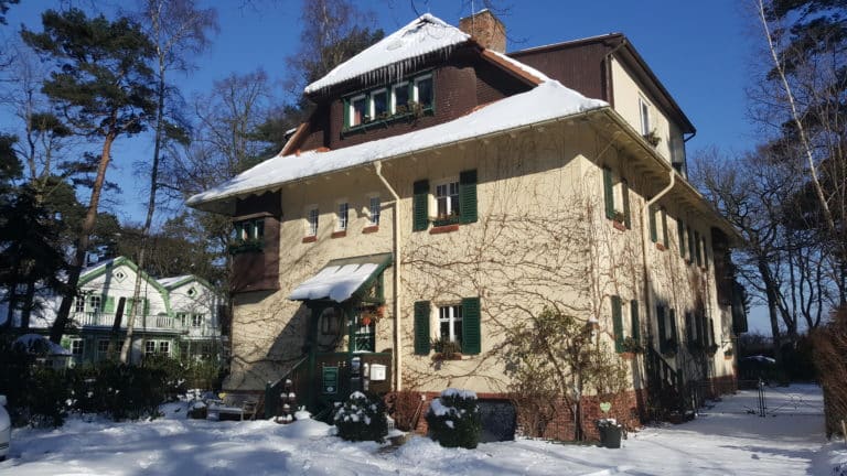 20180228_105158 – Hubertus Boltenhagen Two-story house covered with snow, surrounded by trees.