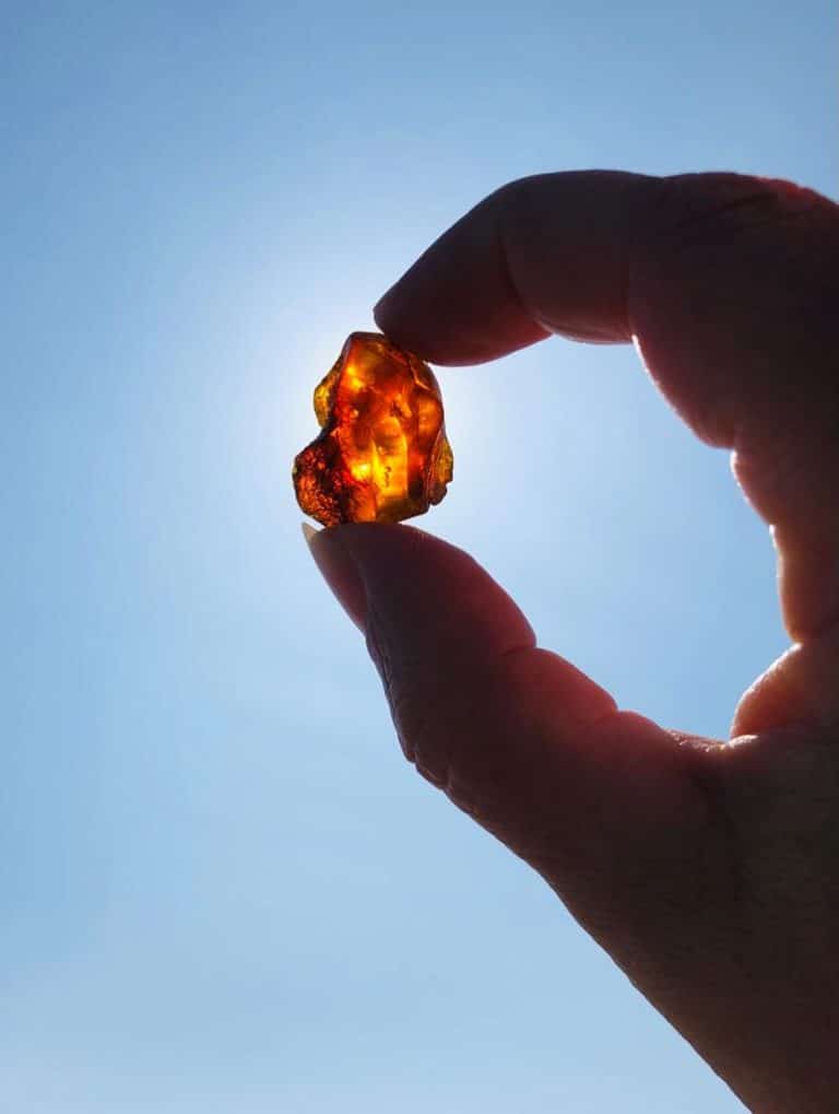 IMG-20210417-WA0001 – Hubertus Boltenhagen Hand holds shining amber against blue sky.