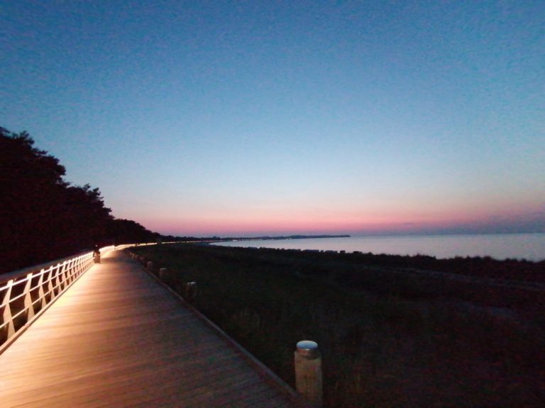 IMG-20220721-WA0000 – Hubertus Boltenhagen Beleuchteter Holzsteg bei Sonnenuntergang am Meer mit rosa-blauem Himmel.