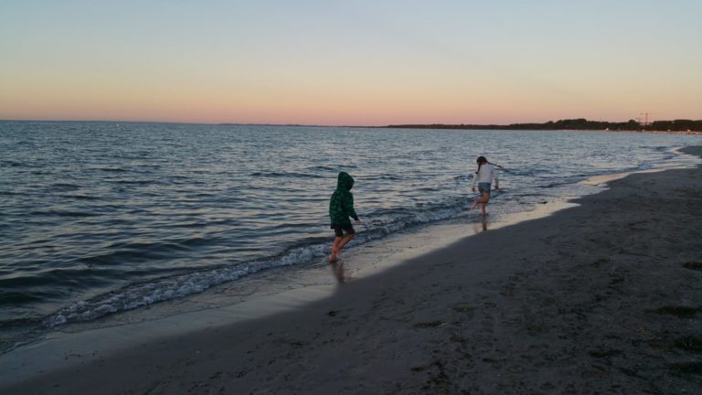 IMG-20220802-WA0002 – Hubertus Boltenhagen Two people walk along the beach in the evening, close to the sea.